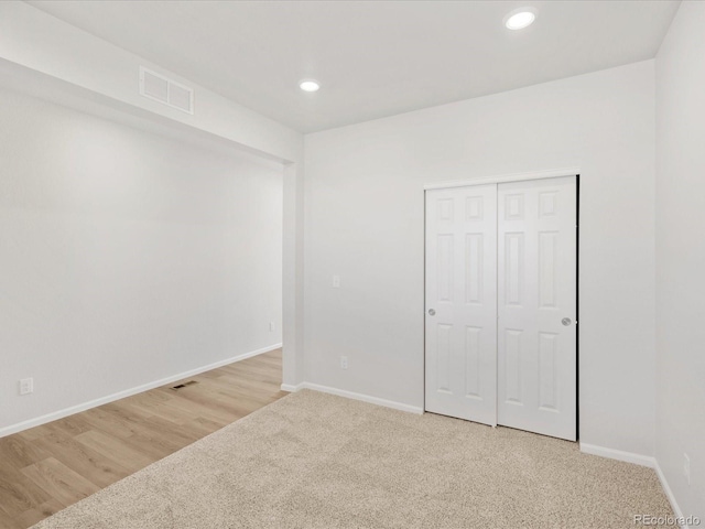 8850 Sedalia St, Commerce City, CO 80022 - unfurnished bedroom with baseboards, recessed lighting, a closet, light carpet, and light wood-style flooring
