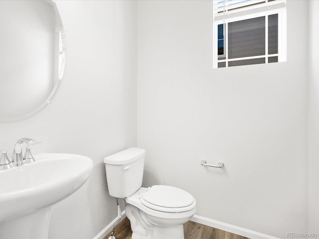8850 Sedalia St, Commerce City, CO 80022 - half bathroom with baseboards, wood finished floors, toilet, and a sink