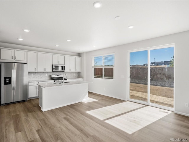 8850 Sedalia St, Commerce City, CO 80022 - kitchen featuring appliances with stainless steel finishes, light wood-type flooring, light countertops, a sink, and white cabinetry