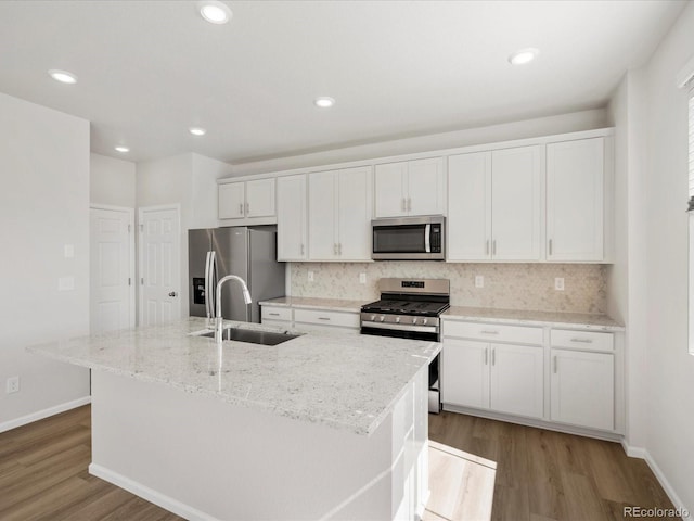8850 Sedalia St, Commerce City, CO 80022 - kitchen with appliances with stainless steel finishes, a sink, wood finished floors, white cabinets, and decorative backsplash