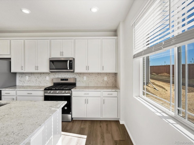 8850 Sedalia St, Commerce City, CO 80022 - kitchen with stainless steel appliances, dark wood-style flooring, white cabinets, backsplash, and light stone countertops