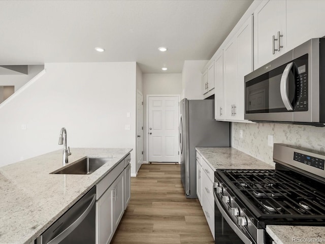 8850 Sedalia St, Commerce City, CO 80022 - kitchen with stainless steel appliances, a sink, white cabinetry, light stone countertops, and recessed lighting