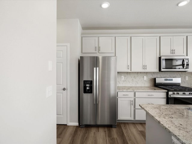 8850 Sedalia St, Commerce City, CO 80022 - kitchen featuring appliances with stainless steel finishes, dark wood-style floors, light stone counters, tasteful backsplash, and recessed lighting