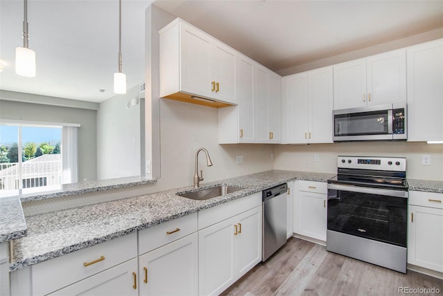 kitchen featuring appliances with stainless steel finishes, hanging light fixtures, and white cabinetry