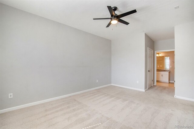 unfurnished bedroom featuring light colored carpet, connected bathroom, baseboards, and ceiling fan