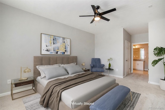 bedroom featuring ensuite bathroom, light colored carpet, and ceiling fan