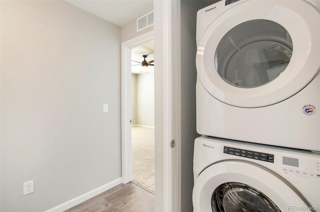 clothes washing area with ceiling fan, stacked washer and clothes dryer, and hardwood / wood-style floors