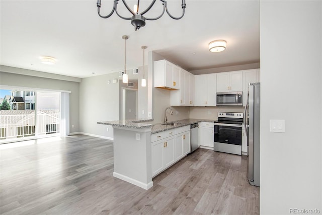 kitchen with light stone countertops, appliances with stainless steel finishes, light wood-style floors, white cabinetry, and a sink