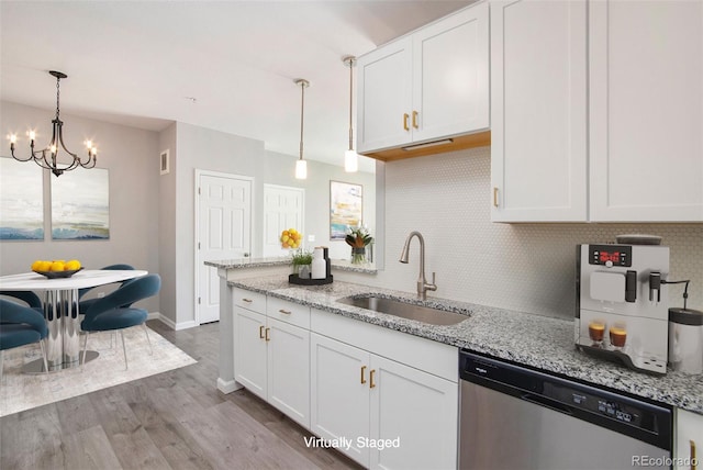 kitchen with hardwood / wood-style floors, light stone counters, white cabinetry, stainless steel dishwasher, and sink