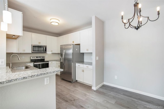 kitchen with white cabinets, stainless steel appliances, hanging light fixtures, and sink