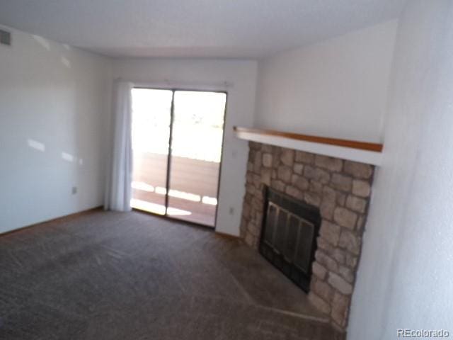 unfurnished living room featuring dark colored carpet and a stone fireplace