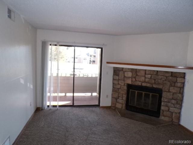 unfurnished living room featuring a textured ceiling, carpet floors, and a fireplace