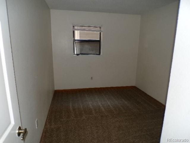 unfurnished room featuring dark carpet