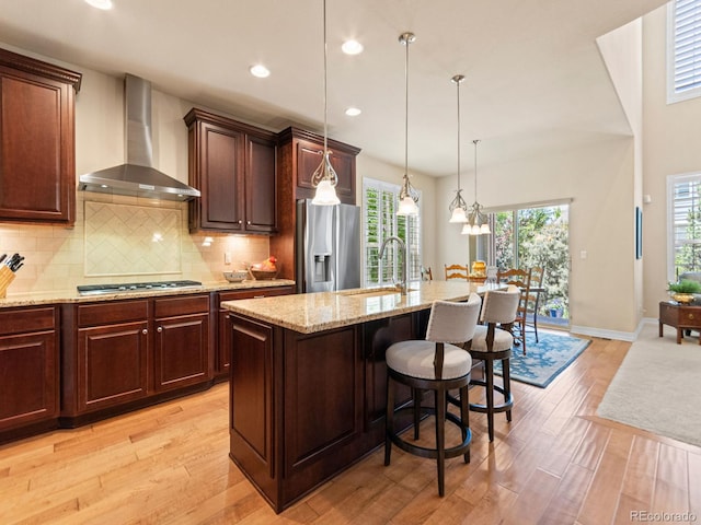 13645 Osage Ct, Broomfield, CO 80023 - kitchen with wall chimney range hood, appliances with stainless steel finishes, light wood-style flooring, recessed lighting, and light stone countertops
