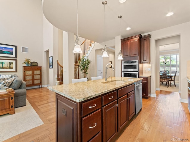 13645 Osage Ct, Broomfield, CO 80023 - kitchen featuring stainless steel appliances, light wood-type flooring, light stone countertops, open floor plan, and recessed lighting