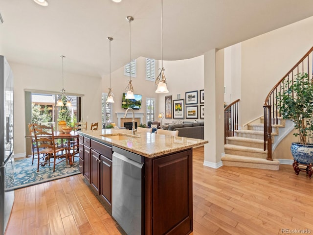 13645 Osage Ct, Broomfield, CO 80023 - kitchen featuring appliances with stainless steel finishes, light wood-type flooring, dark brown cabinets, light stone countertops, and open floor plan