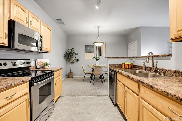 kitchen with stainless steel appliances, a sink, light brown cabinetry, and light carpet