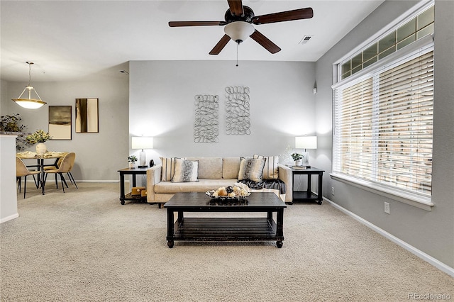 carpeted living room featuring a ceiling fan and baseboards