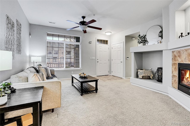 carpeted living room with a tile fireplace, ceiling fan, and baseboards