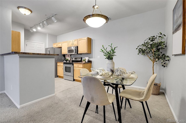 dining space featuring light carpet, track lighting, and baseboards