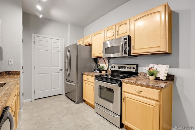kitchen with stainless steel appliances, light brown cabinetry, and dark countertops