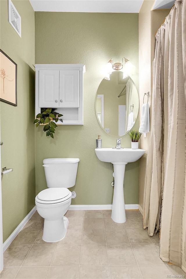 bathroom with toilet, tile patterned flooring, and baseboards