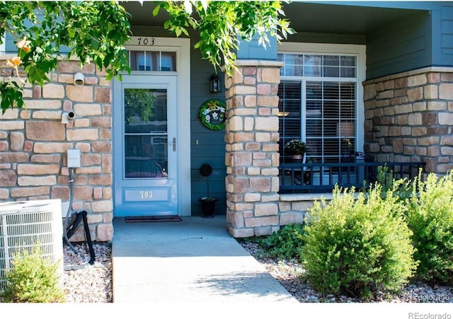 457 Black Feather Loop Unit 703, Castle Rock, CO 80104 - doorway to property with central AC unit, brick siding, and covered porch