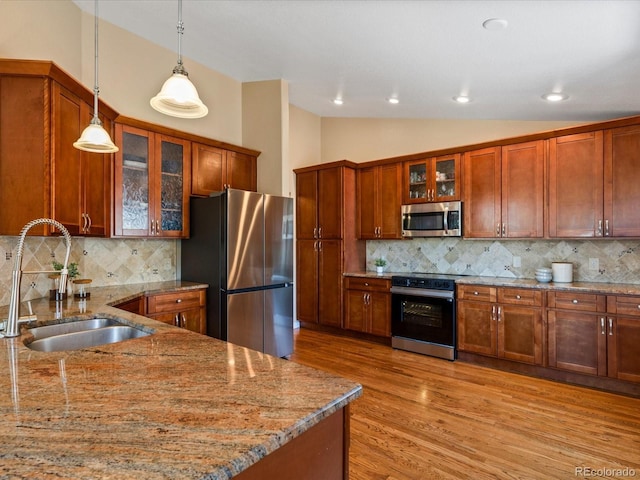 885 Sage Sparrow Cir, Highlands Ranch, CO 80129 - kitchen with appliances with stainless steel finishes, pendant lighting, lofted ceiling, tasteful backsplash, and light wood-style flooring