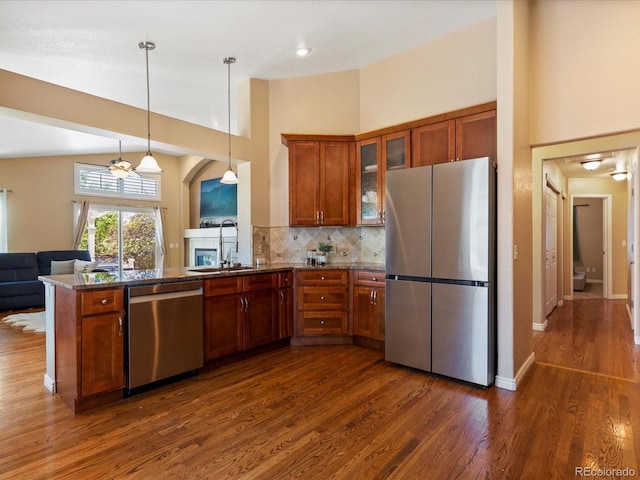 885 Sage Sparrow Cir, Highlands Ranch, CO 80129 - kitchen featuring appliances with stainless steel finishes, brown cabinetry, a peninsula, dark wood-style flooring, and glass insert cabinets