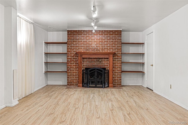 unfurnished living room with light hardwood / wood-style floors and a brick fireplace