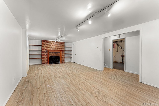 unfurnished living room featuring light hardwood / wood-style floors, track lighting, and a fireplace