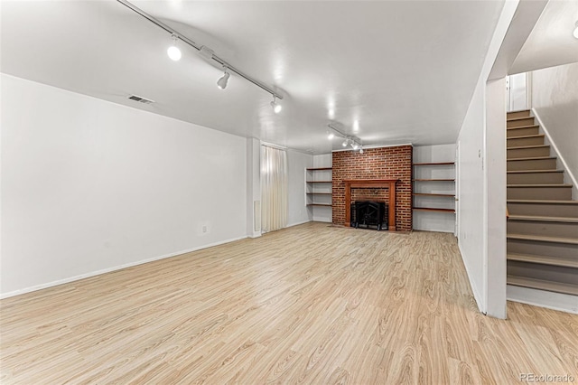 unfurnished living room with light hardwood / wood-style flooring, track lighting, and a fireplace