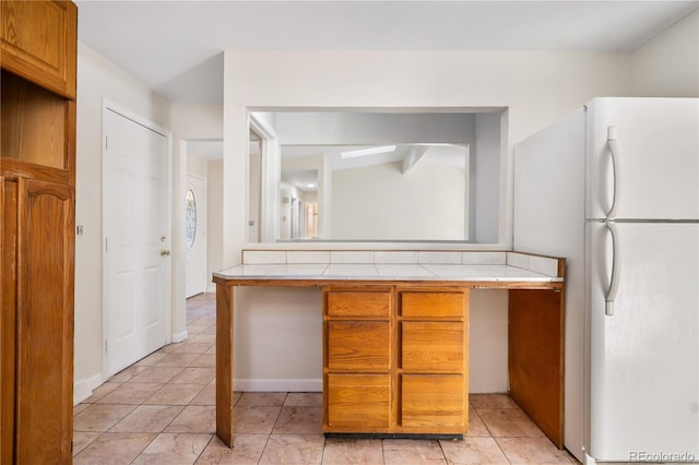 kitchen featuring tile counters and white fridge