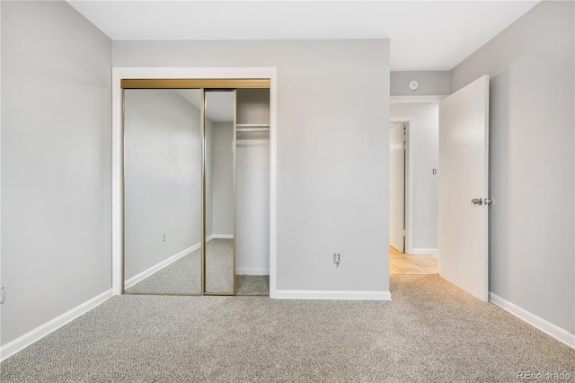 unfurnished bedroom with light carpet and a closet