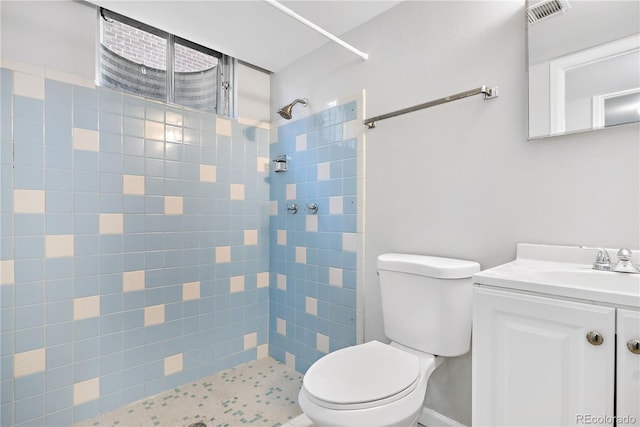 bathroom featuring toilet, a tile shower, and vanity