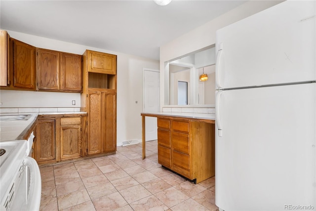 kitchen featuring sink, hanging light fixtures, white refrigerator, tile countertops, and stove