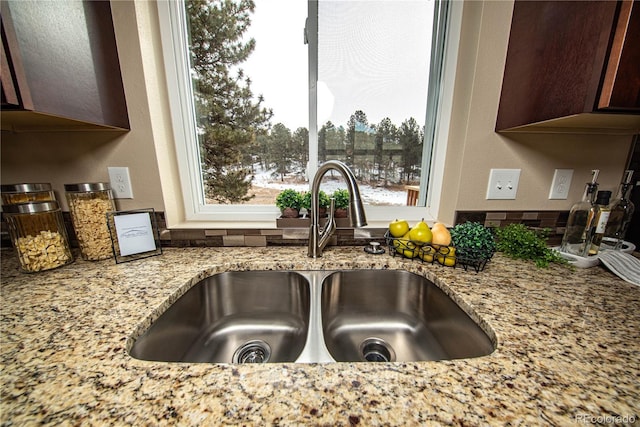 room details with light stone countertops, dark brown cabinetry, and sink