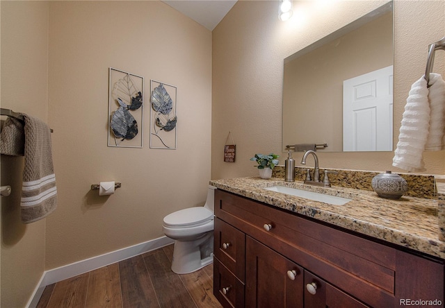 bathroom with hardwood / wood-style floors, vanity, and toilet