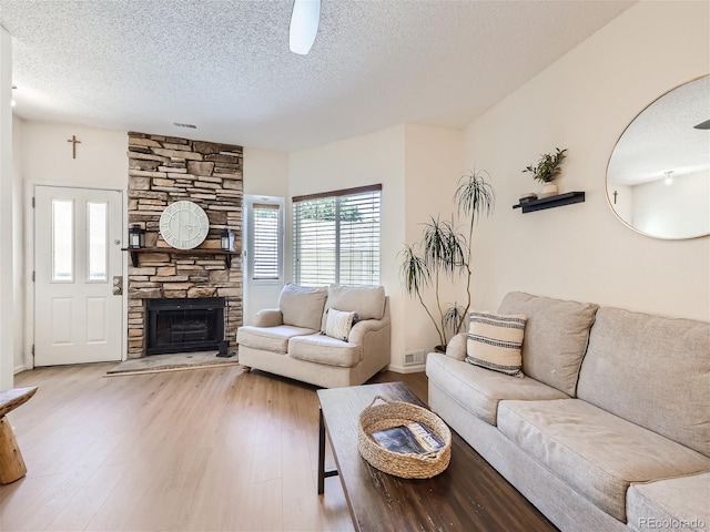 living room featuring a fireplace, light hardwood / wood-style floors, and a textured ceiling