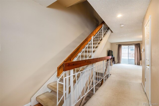 staircase featuring recessed lighting, a textured ceiling, and carpet