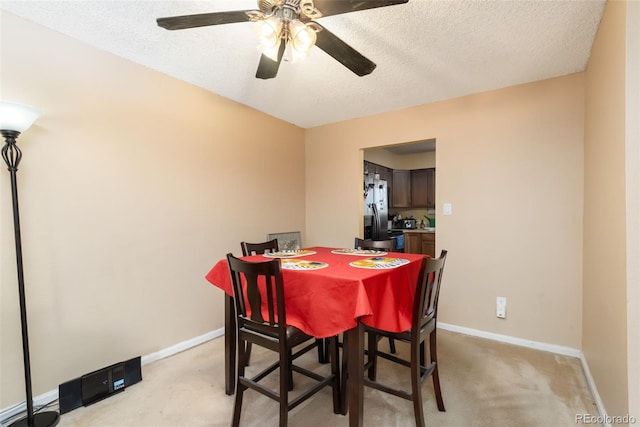 dining space featuring baseboards, a ceiling fan, a textured ceiling, and light colored carpet