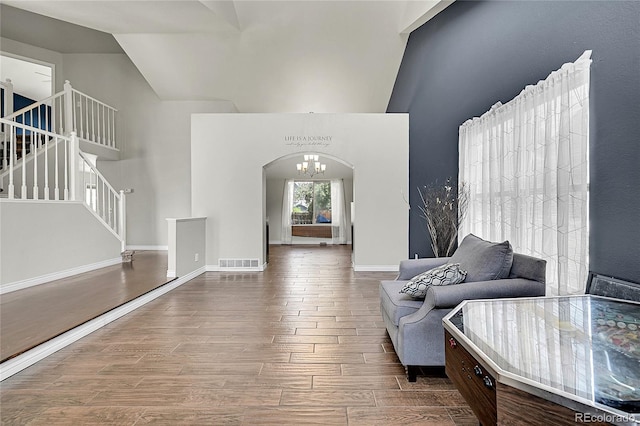 3163 E 133rd Ave, Thornton, CO 80241 - living room with high vaulted ceiling, stairs, wood finished floors, a chandelier, and arched walkways