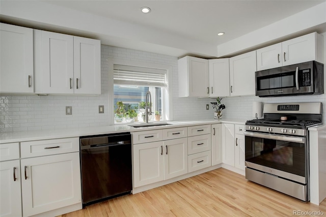 kitchen featuring light countertops, light wood-style flooring, appliances with stainless steel finishes, white cabinetry, and a sink