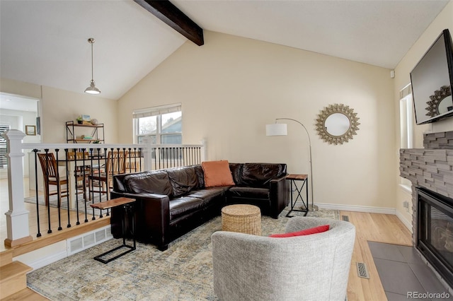 living area with a fireplace, visible vents, baseboards, beam ceiling, and light wood finished floors