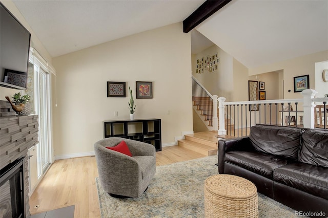 living area with vaulted ceiling with beams, a stone fireplace, light wood-type flooring, and baseboards