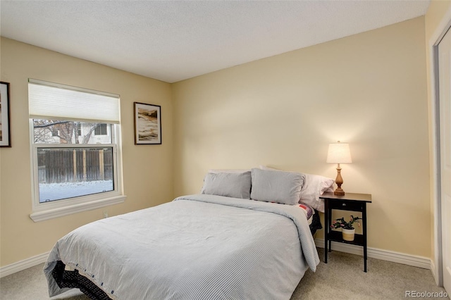 bedroom with light carpet, a textured ceiling, and baseboards