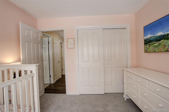 bedroom with dark colored carpet, a closet, and a textured ceiling