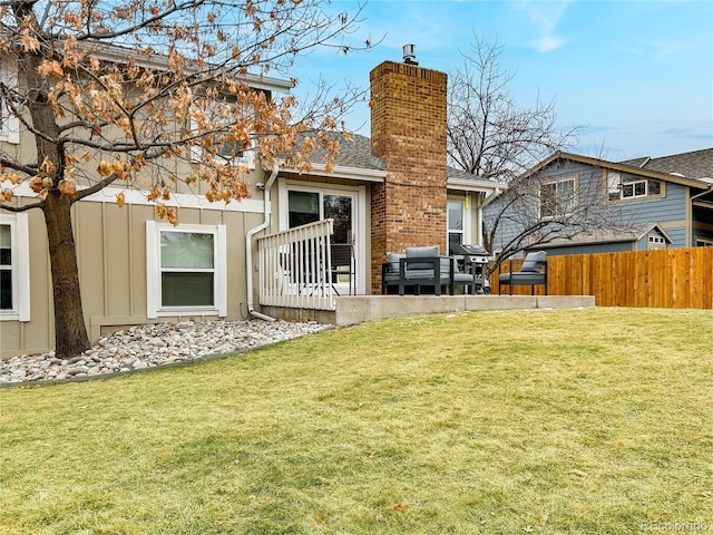 rear view of property with a yard, a chimney, fence, and roof with shingles