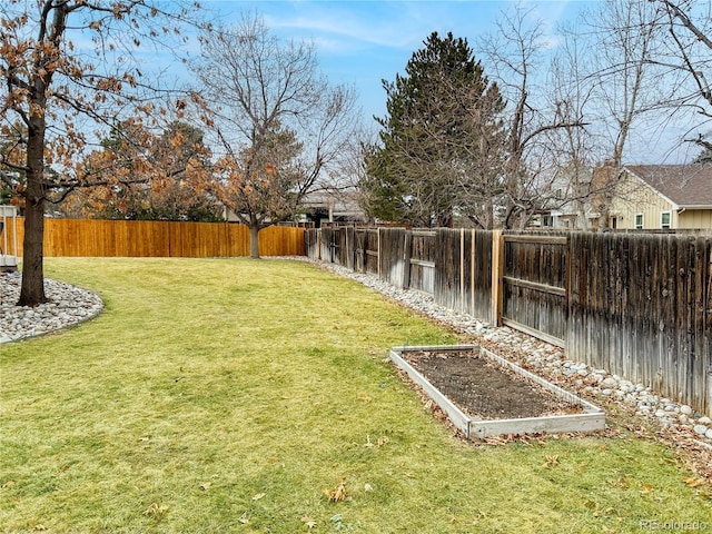 view of yard featuring a water view, a fenced backyard, and a vegetable garden