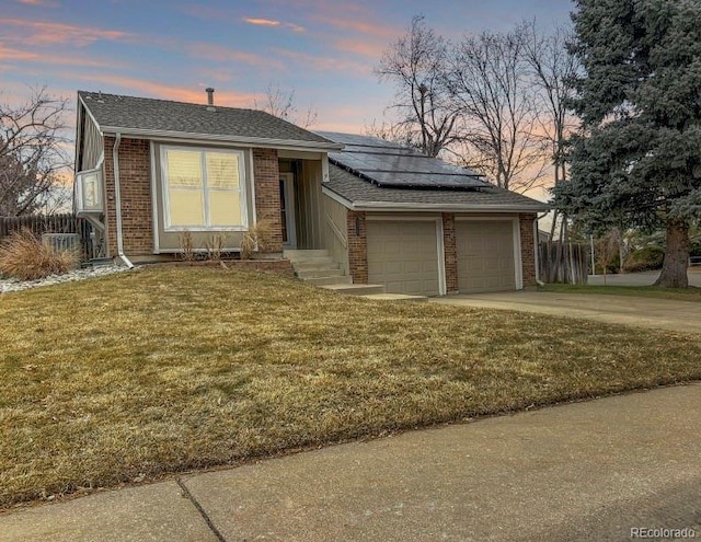 view of front of home with a garage, roof mounted solar panels, concrete driveway, and brick siding